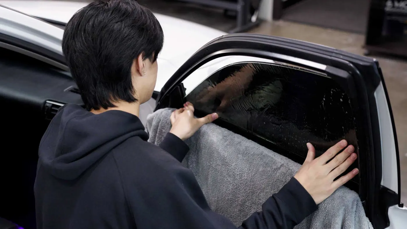 Cincinnati Car Tinting installer applying window tint film to a car window in Cincinnati, Ohio
